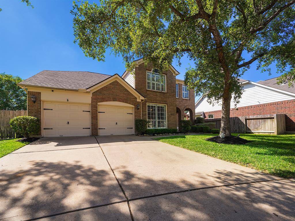 The property features a classic brick exterior enhanced by mature trees and lush landscaping, creating a welcoming ambiance.
