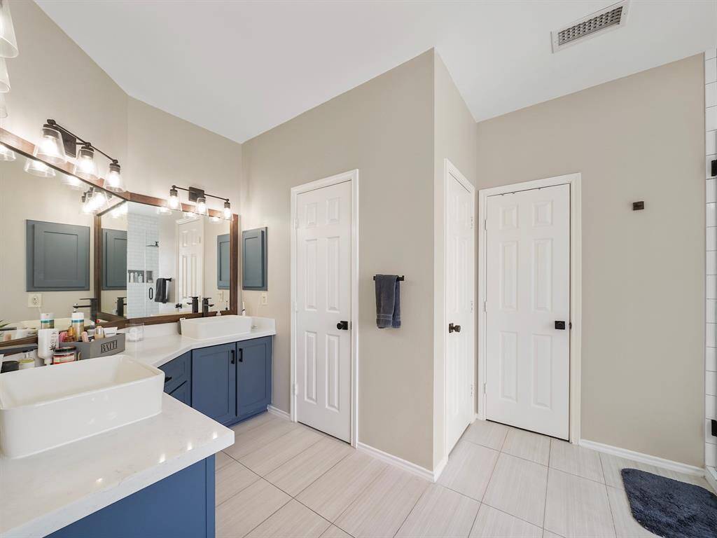 Indulge in the gorgeous primary ensuite, boasting a beautiful blue vanity with ample storage, elegant quartz countertops, and dual vessel sinks for a luxurious experience.