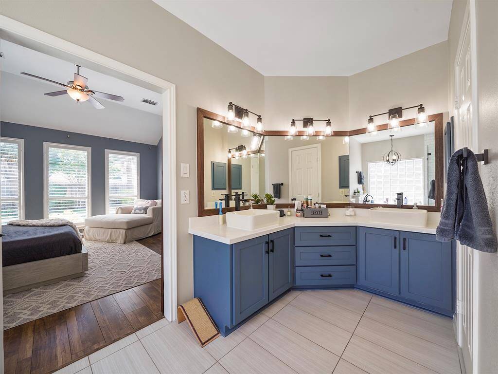 This updated ensuite bathroom features a modern vanity with ample storage, complemented by a stylish framed mirror and elegant vanity lighting for a bright and sophisticated space.