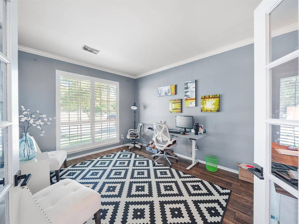 French doors from the entryway unveil a private office, adorned with plantation shutters and exquisite crown molding. Perfect for remote work or quiet contemplation, this space seamlessly blends functionality with sophisticated design.
