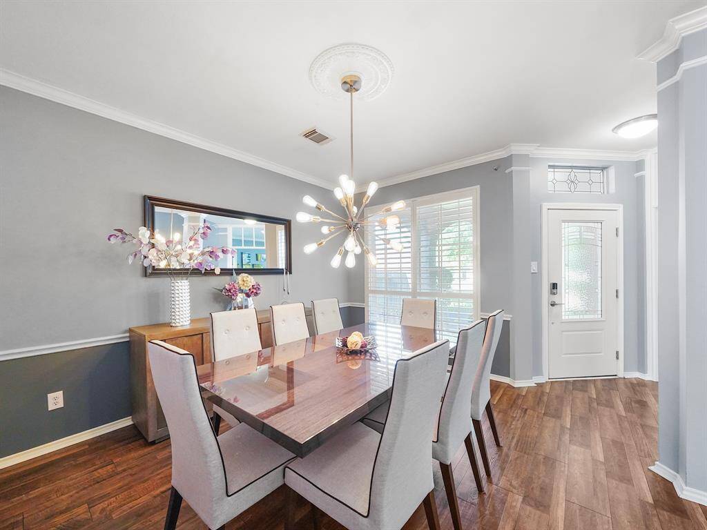 Discover the elegant formal dining area, featuring classic chair railing, a contemporary light fixture, and stylish plantation shutters. Perfect for creating unforgettable dining experiences.