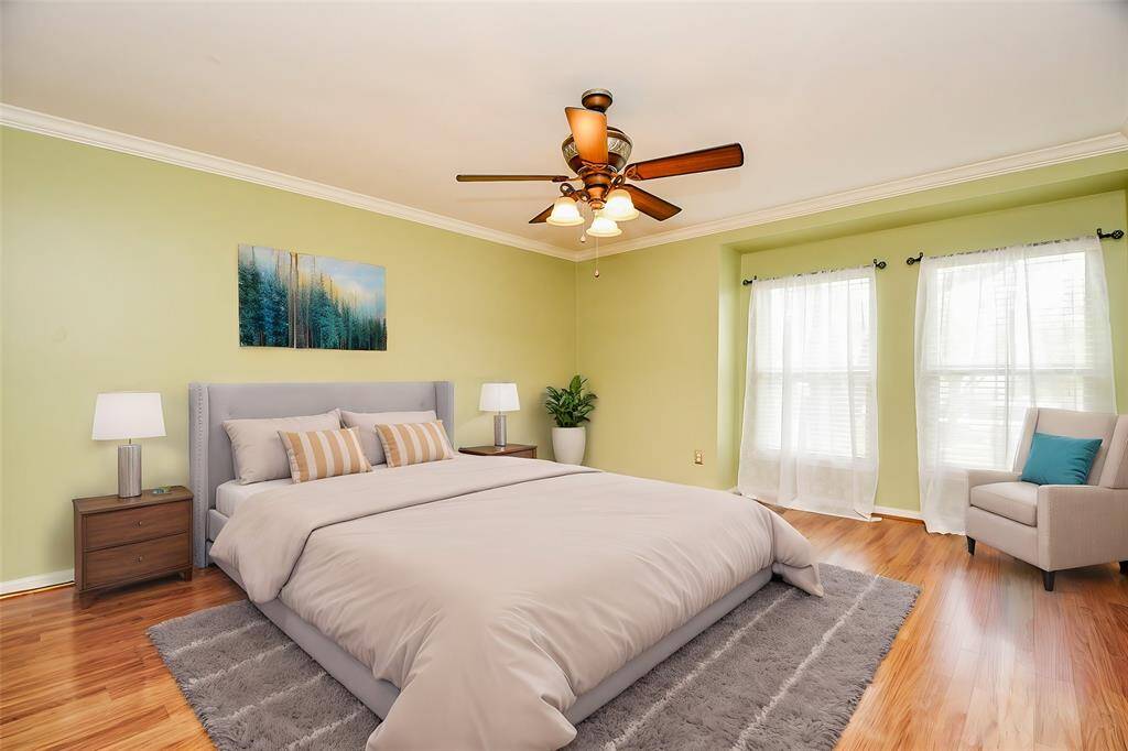 Large primary bedroom overlooking the park with laminate wood flooring. (virtually staged)
