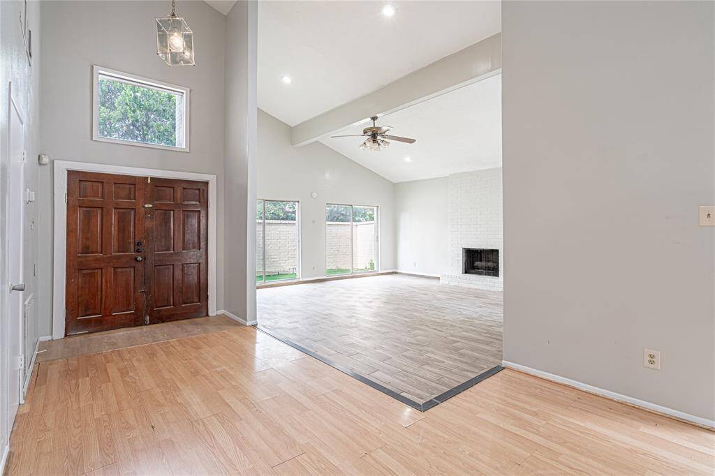 The front entrance opens into a spacious family room with soaring ceilings, tons of natural light, and a cozy fireplace.