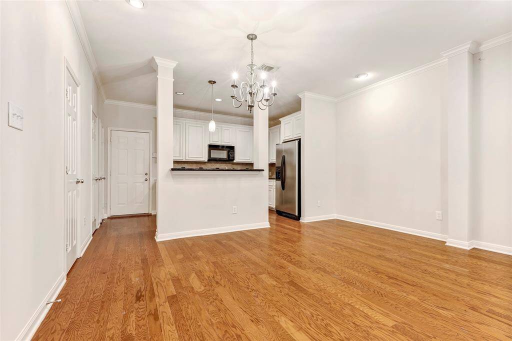Beautiful light fixtures brighten up the empty living room and kitchen, highlighting the space’s potential.