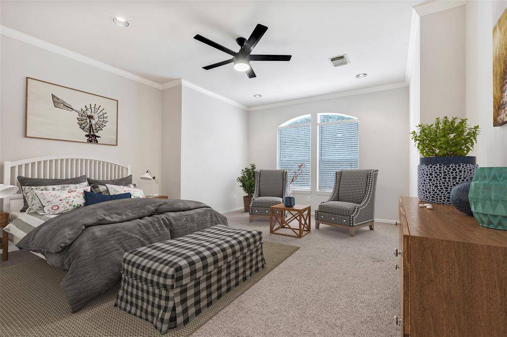This spacious primary bedroom has carpeted floors, ceiling fan, and a large glass window for plenty of natural light. (Virtually Staged)