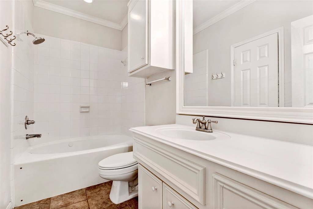 En-suite bathroom, featuring a tub and shower combo with ample cabinet storage for added convenience.