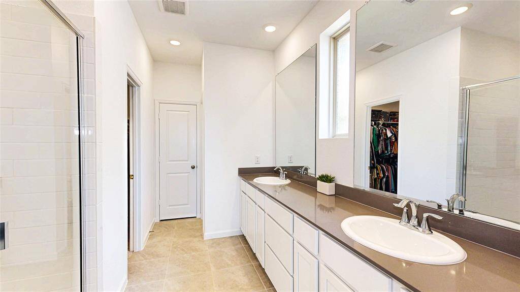 Bright primary bath with double sinks, large mirrors, and a walk-in shower.