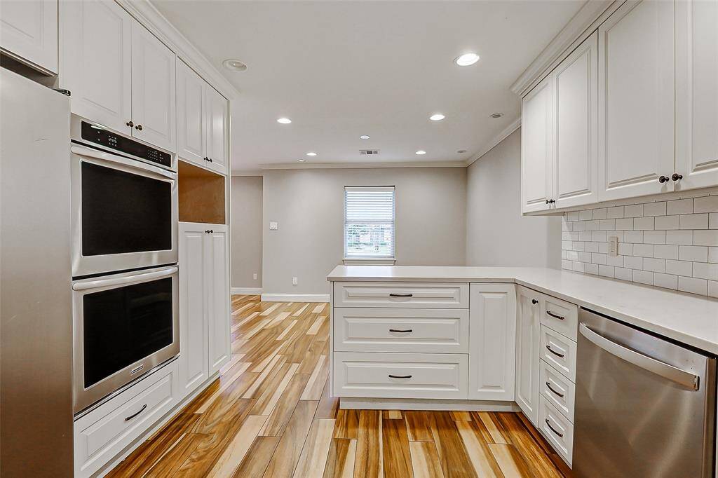 From this angle, you’ll notice the classic subway tile backsplash that perfectly complements the sleek countertops. A built-in dishwasher sits conveniently to the left of the sink, making cleanup a breeze.