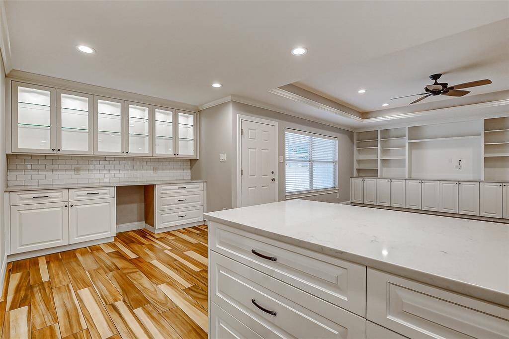 Adjacent to the kitchen, this charming area offers both cabinetry and countertop space, along with a versatile seating nook that can serve multiple purposes. The upper cabinets feature glass fronts, providing the perfect space to showcase your favorite dishware and decor.