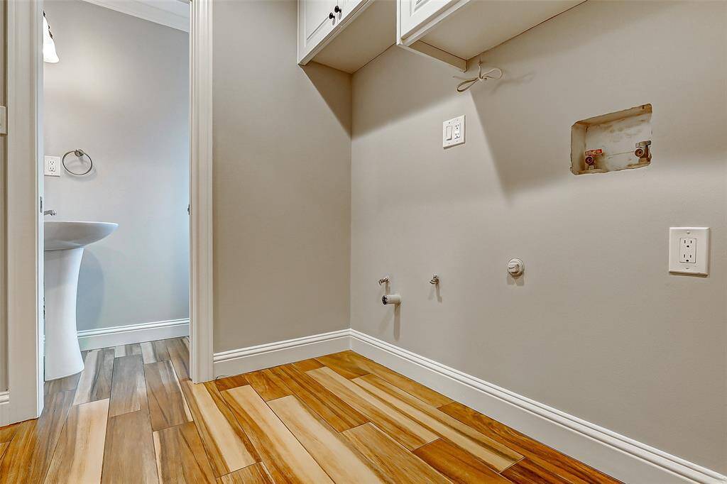 The utility room, featuring built-in cabinets for added storage, is conveniently located near the half bathroom, which includes a sleek pedestal sink.