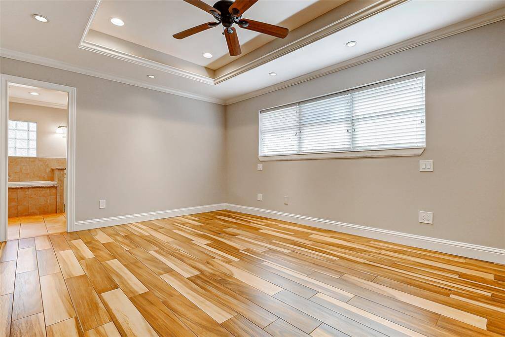 Welcome to your elegant primary suite, where tray ceilings, a ceiling fan, crown molding, and recessed lighting come together to create a serene and sophisticated retreat