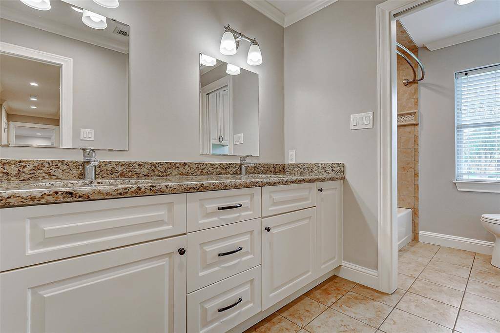 Guests will appreciate this spacious full bathroom, featuring a large vanity with dual sinks, sleek granite countertops, and crisp white cabinetry—blending style and functionality beautifully.