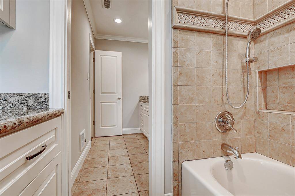 The bathroom also includes a tub/shower combination with a neutral tile surround, along with an additional vanity featuring granite countertops. Tucked away, this area provides added privacy, making it a perfect retreat for guests.