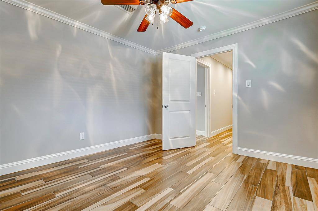 Guest bedroom number three boasts wood-look tile floors, decorator paint, crown molding, and a ceiling fan. With plenty of space, it’s perfect for family or guests to feel right at home.