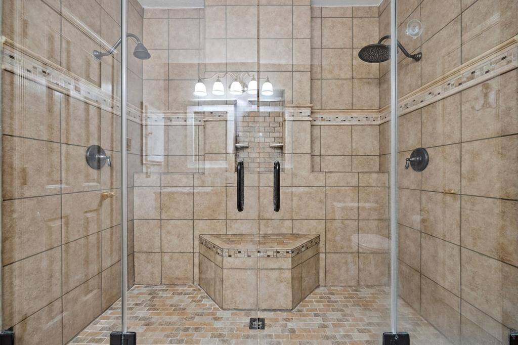 Oversized shower with seating bench and frameless glass doors