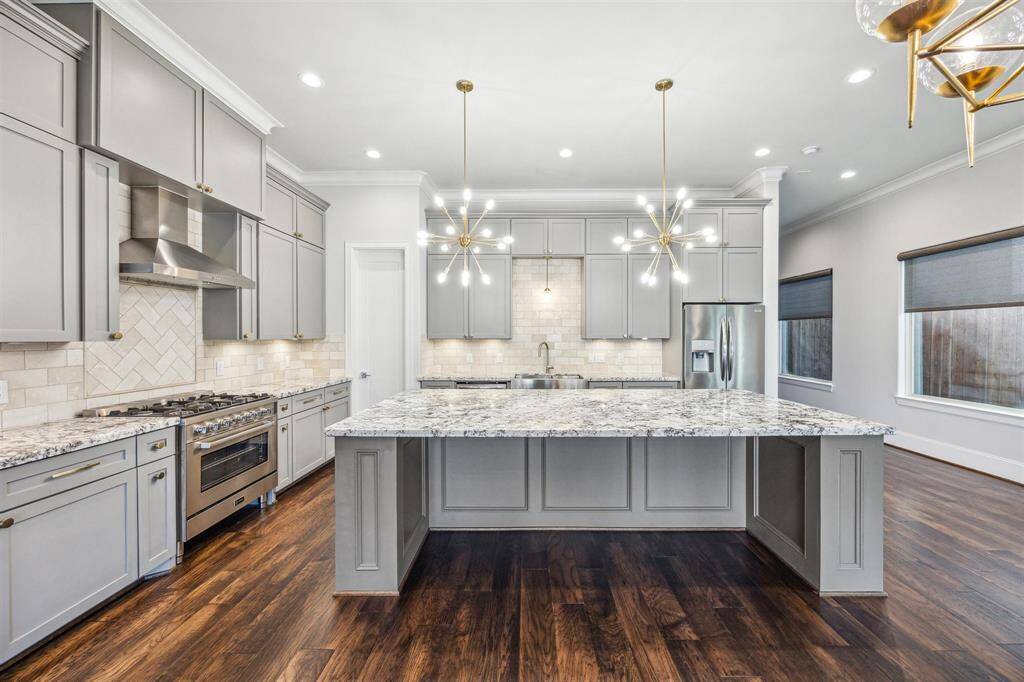 A large island with breakfast bar with space for seating for casual dining, and highlighted by chic pendant lighting.