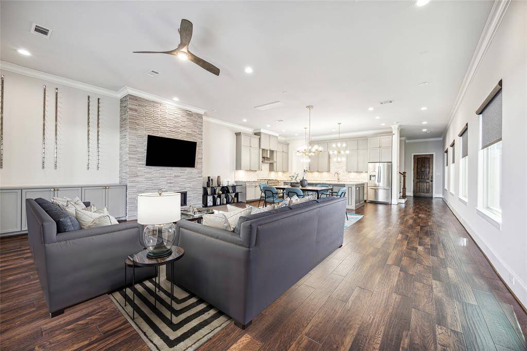 **Virtually Staged** Open-concept design connecting the living, dining, and kitchen areas with rich hardwood flooring, recessed lighting, and modern gold light fixtures.