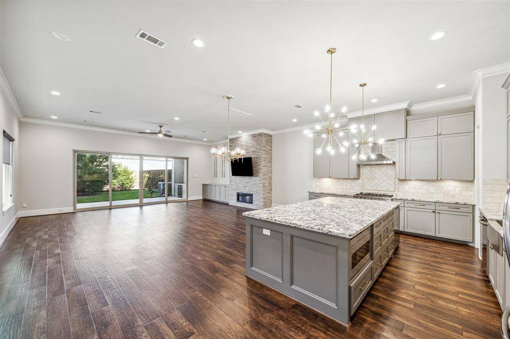 This angle highlights the kitchen’s open flow, with the island and breakfast bar connecting to the dining space under modern light fixtures.
