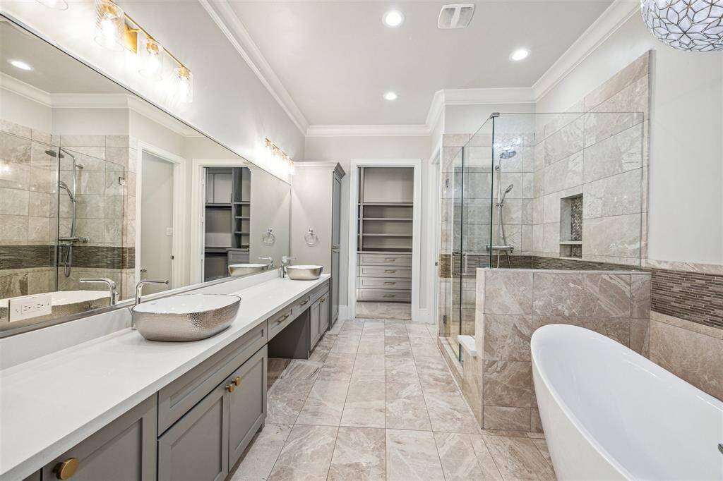 The primary bathroom boasts dual hammered metal vessel sinks, porcelain countertops, separate water closet, custom cabinetry, and a spa-like soaking tub alongside a glass-enclosed walk-in shower.