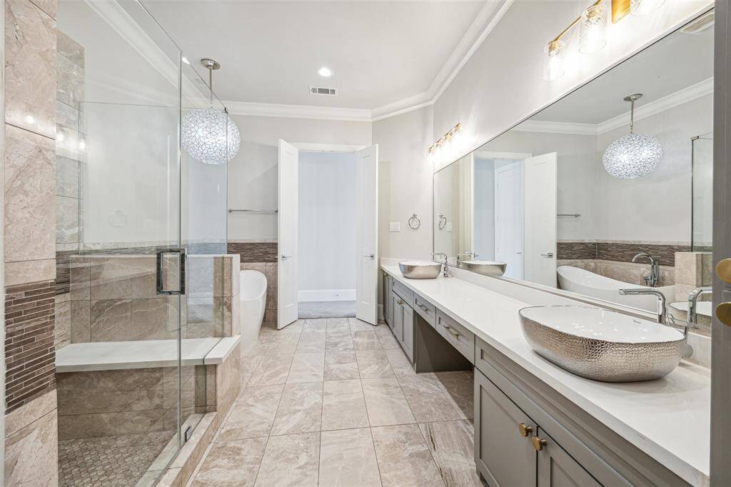 The spacious shower area with custom tile work, a frameless glass enclosure, and built-in seating for added comfort.
