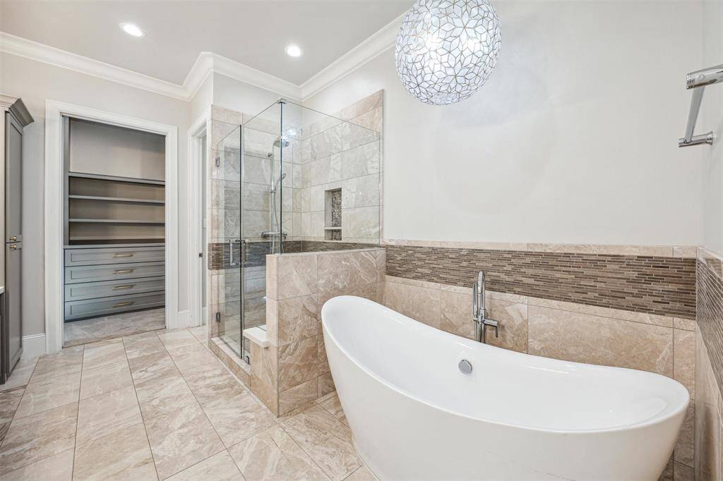 A close-up of the stunning freestanding soaking tub, paired with designer lighting, mosaic tile accents and elegant fixtures.