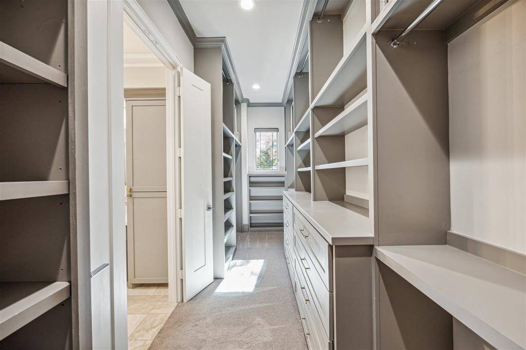Luxurious primary walk-in closet with built-in shelving, drawers, and ample hanging space, designed for functionality and style.