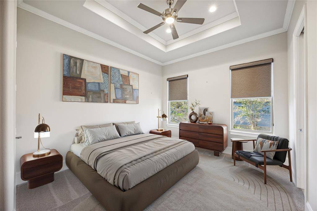 **Virtually Staged** A bright and spacious bedroom with a tray ceiling, large windows, neutral carpet, and access to a secondary bathroom, perfect for guests or family members.