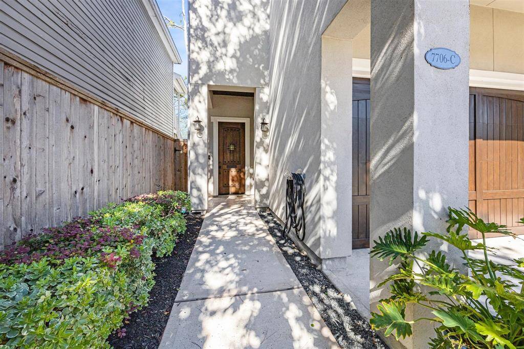 The elegant entryway is complemented by a sleek dark-stained front door with wrought-iron accents.