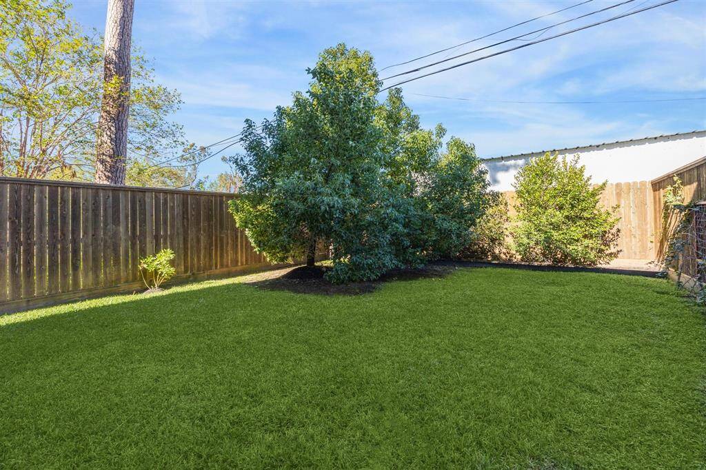 A spacious and private backyard with manicured grass, a wooden privacy fence, and landscaped accents, ideal for entertaining or relaxing.