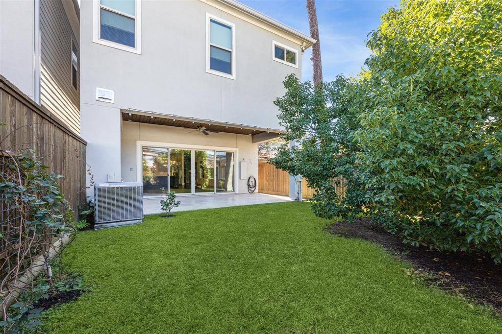 The covered patio extends into the backyard, showcasing the travertine tile flooring and an uninterrupted view of the outdoor space.