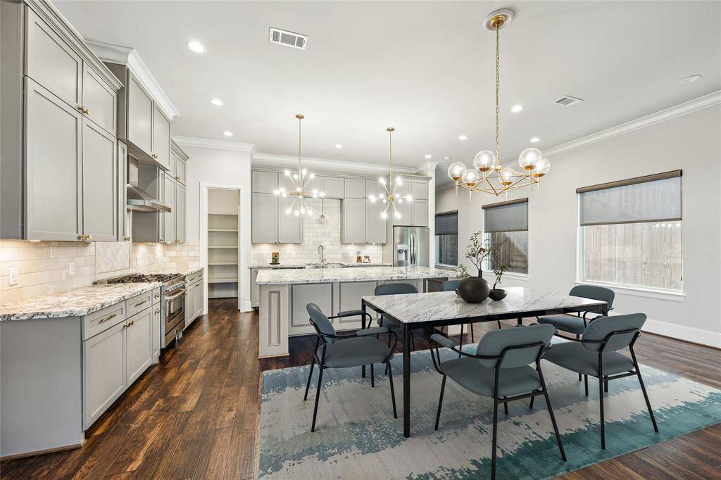**Virtually Staged** The dining space is enhanced by an elegant chandelier, large windows with custom shades, and seamless access to the kitchen.