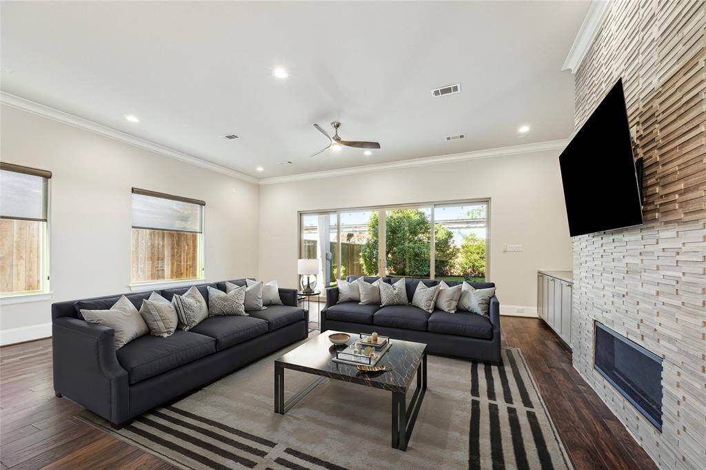 **Virtually Staged** The expansive living area features custom built-ins, a modern stacked stone fireplace, and oversized sliding glass doors leading to the backyard, allowing natural light to flood the space.