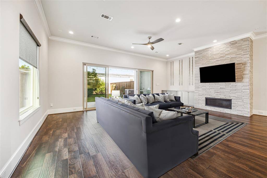 **Virtually Staged** Another perspective of the living room, focusing on the built-ins w/ wine bottle storage, stacked stone fireplace, and sliding doors leading to the covered patio.