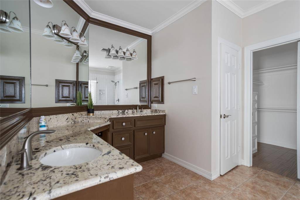 Primary bathroom with double sinks, vanity, and walk in closet