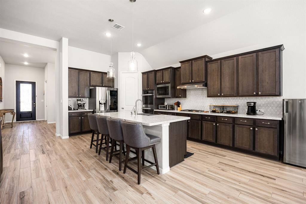 This gourmet kitchen is a chef's paradise, boasting elegant maple cabinets, sleek quartz countertops, and a charming farmhouse sink.