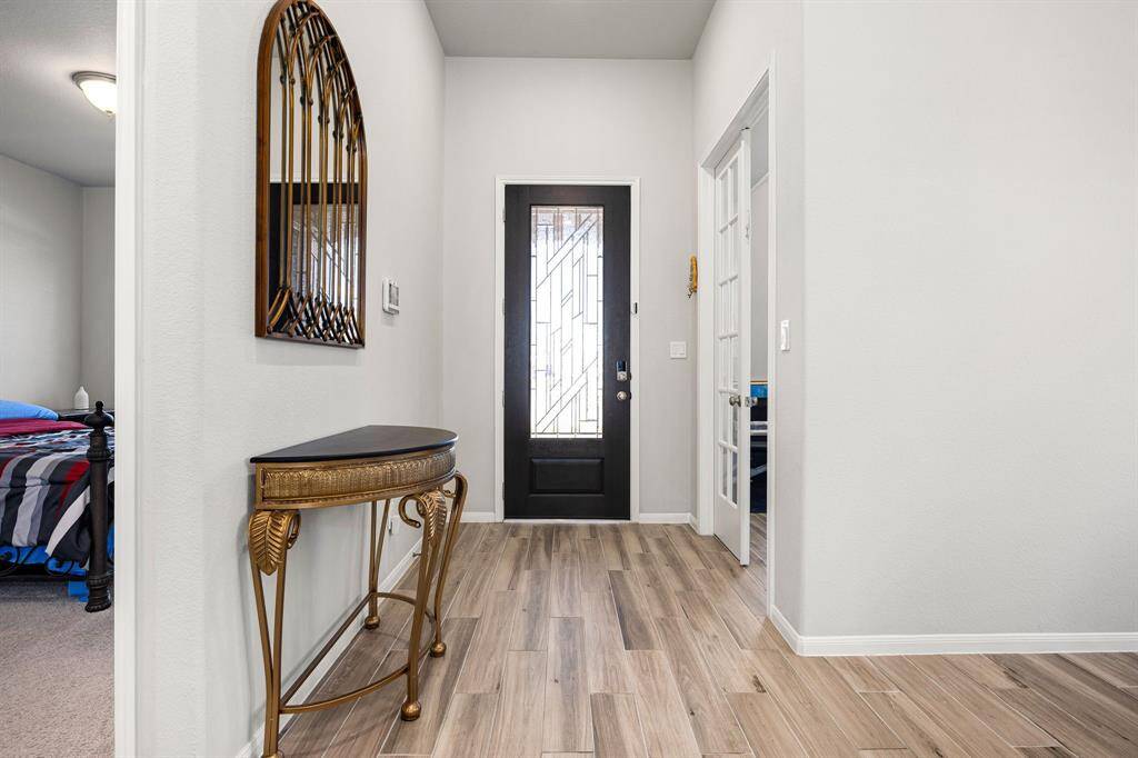 Upon entering, you are greeted by a welcoming foyer that leads to a convenient home office with elegant French doors and an open dining room