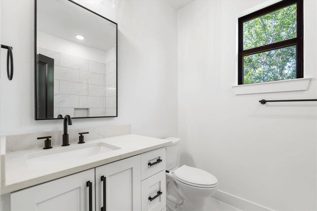 The third full bathroom showcases a walk-in shower, a sleek modern mirror, and a quartz countertop with striking black accents.