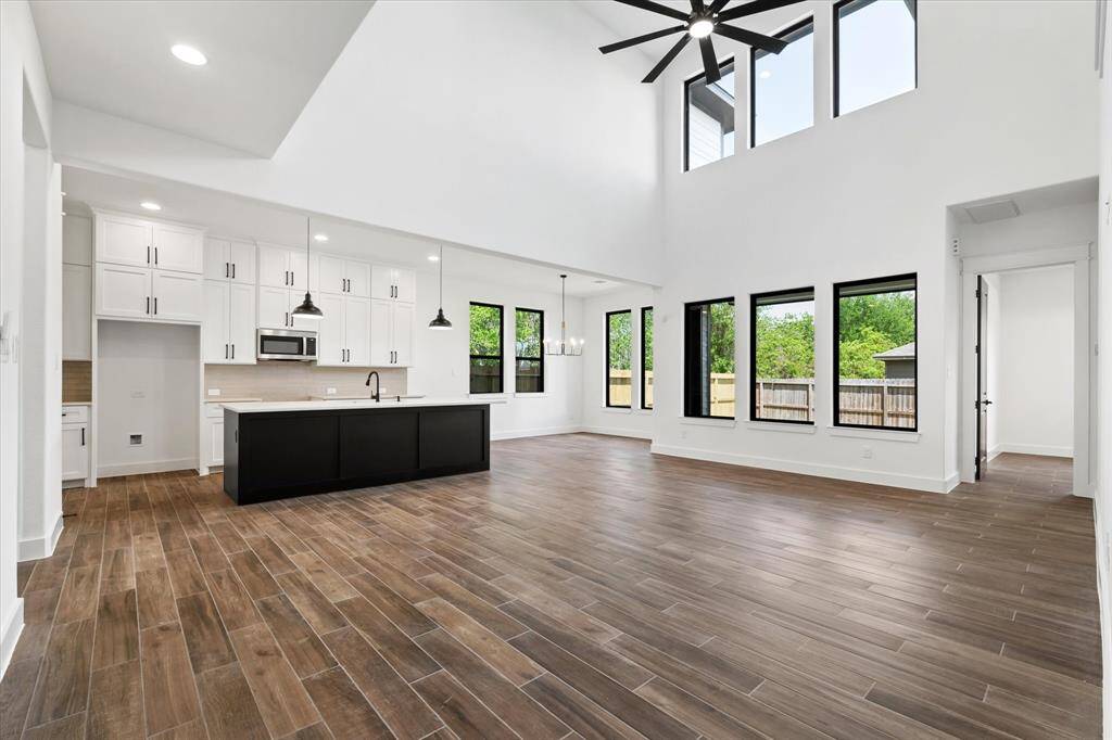 The living room features elegant tile flooring, recessed lighting, soaring ceilings, and expansive picture windows that offer a stunning view .