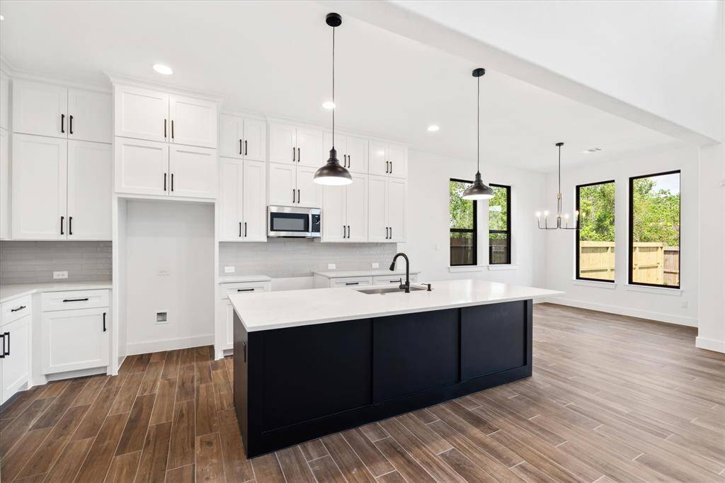 A spacious kitchen with custom cabinetry up to the ceiling, a must-have island with pendant lights and black accents throughout.