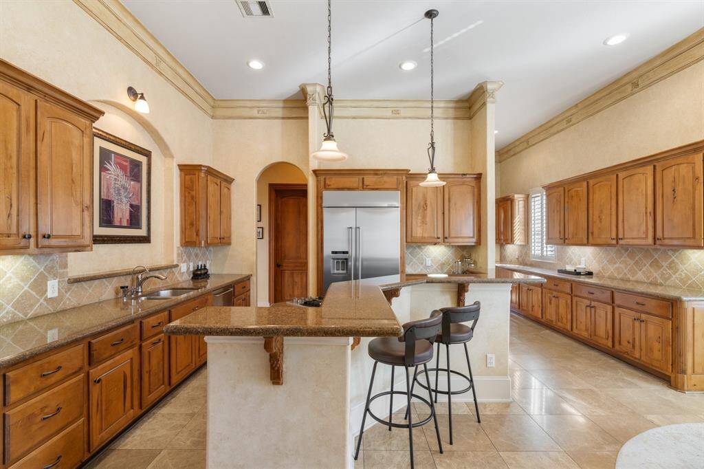 This beautiful and spacious KITCHEN is designed for both functionality and style, featuring granite countertops, a stone backsplash, and tons of storage. The breakfast bar, adorned with decorative pendant lighting, is perfect for casual dining. Notice the breakfast nook for additional dining space. Other highlights include double crown molding, recessed can lighting and under cabinet lighting. Not shown is a large walk-in pantry.