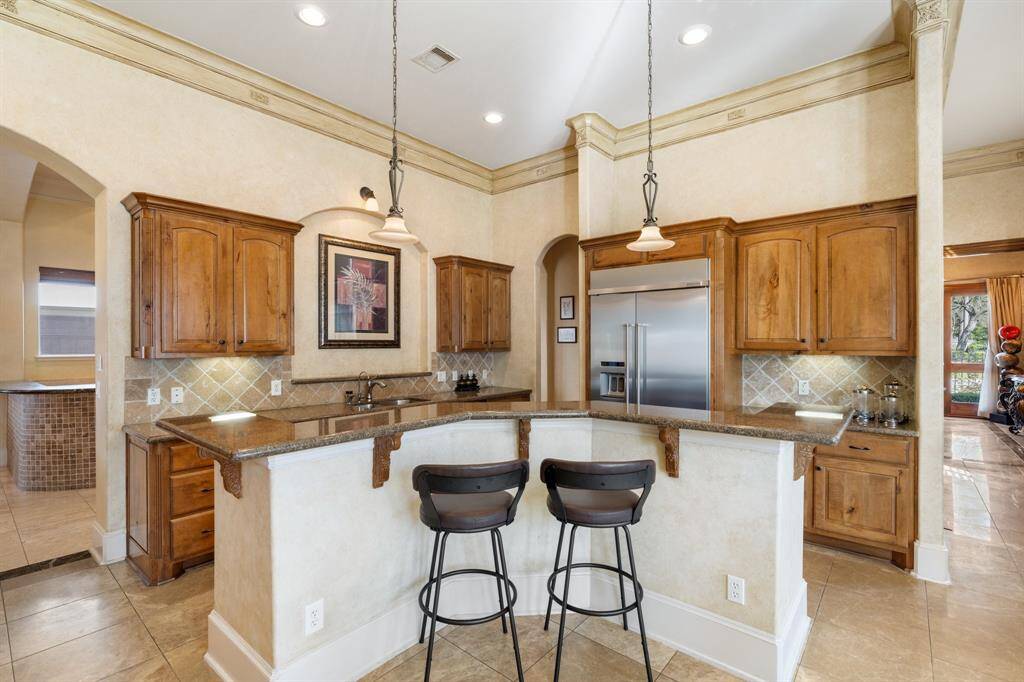 This fabulous kitchen boasts high-end stainless steel appliances including dual GE ovens, a built-in GE microwave, a 5-burner Jenn-Air gas cooktop, and a built-in KitchenAid refrigerator and freezer. Ample storage space. There is a double basin stainless steel sink, an instant hot water dispenser, and a filtered water dispenser.