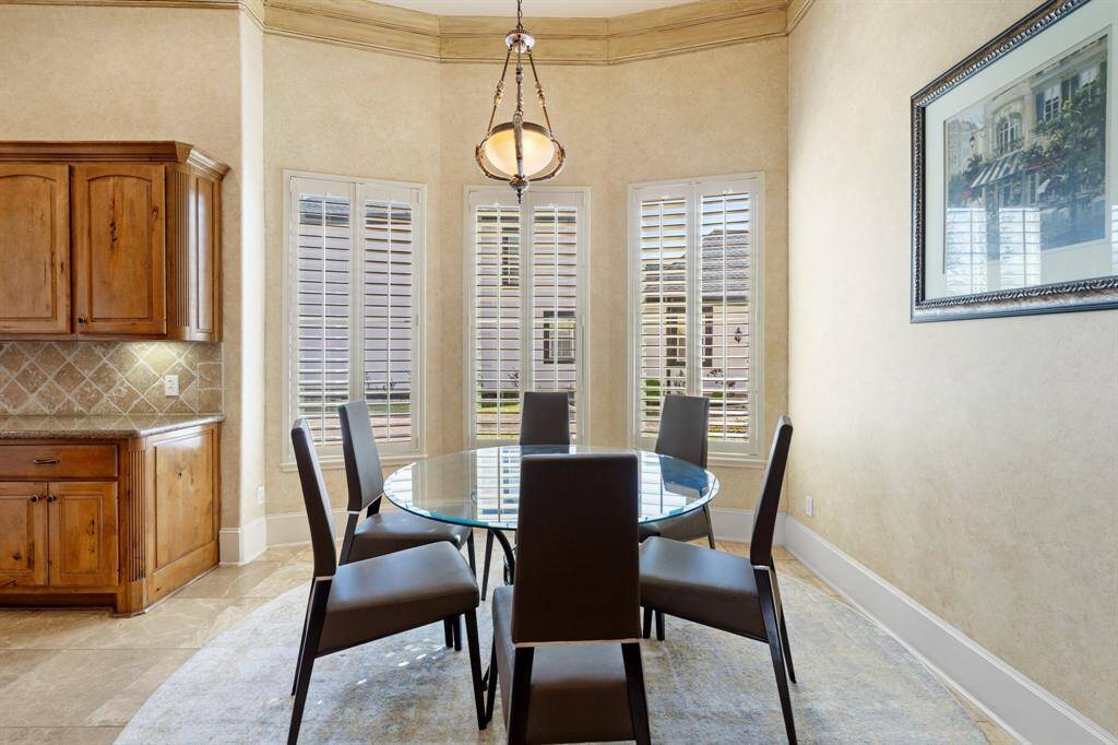 Charming BREAKFAST AREA is highlighted by a decorative light fixture and double crown molding. Plantation shutters add both elegance and privacy, creating the perfect space for casual everyday dining.
