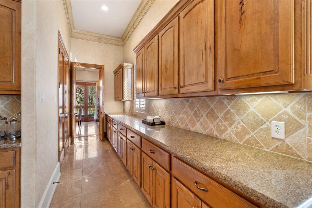 This large butler’s pantry with abundant storage and granite counters leads to the formal dining room. Notice the double door closet, providing additional storage space.