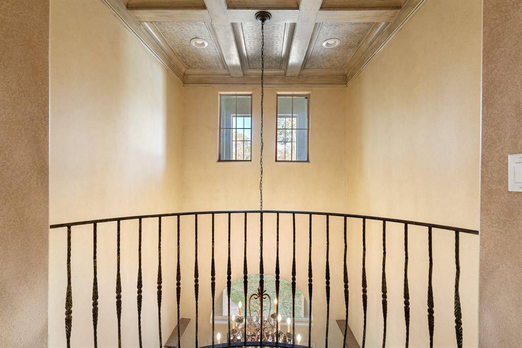 A look at the double height ceiling of the entryway with coffered ceiling and chandelier. A beautiful view just outside the elevator and the primary suite.