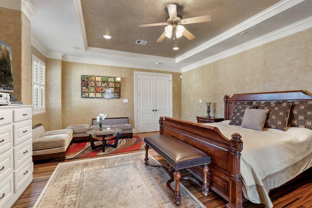 Located upstairs, this oversized PRIMARY SUITE offers a generous sitting area, perfect for relaxation. Hand-painted textured walls and crown molding add elegance, and the built-in dresser/media center offers added convenience. Plantation shutters, tray ceiling, recessed can lighting, ceiling speakers, ceiling fan/light fixture and hardwood floors complete the luxurious feel of this retreat.
