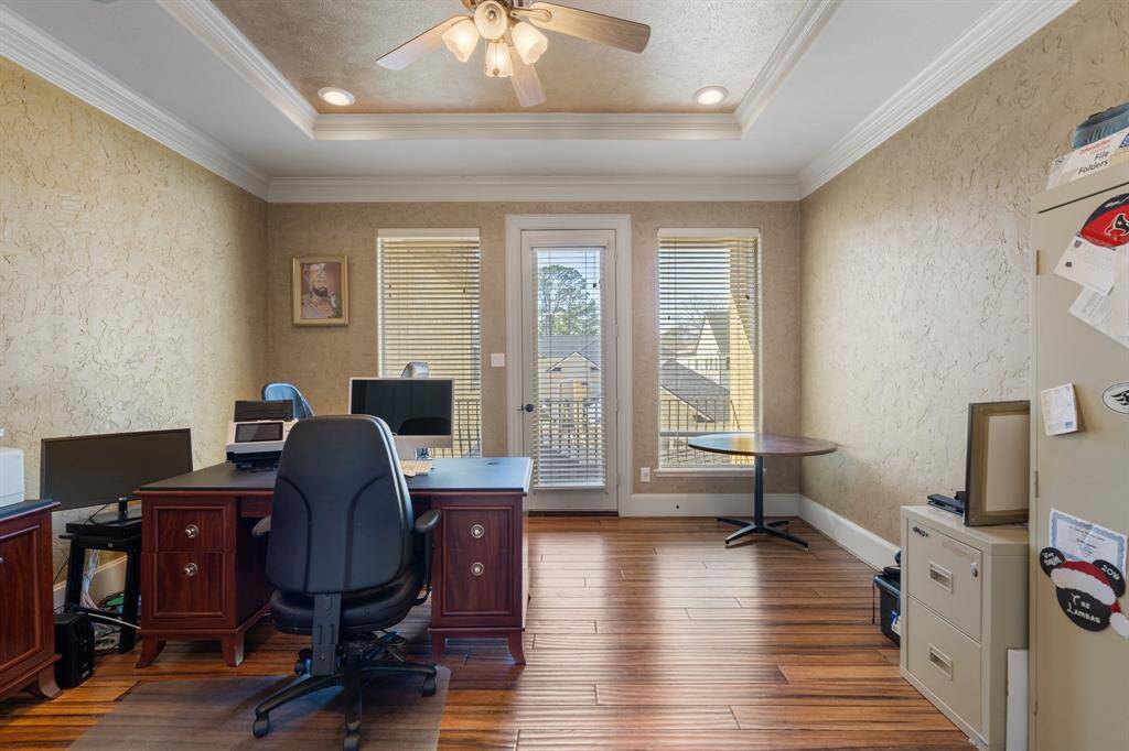 Double doors lead from the primary bedroom to this fabulous HOME OFFICE, a flexible space that could also function as a home gym, nursery, sitting room, or even an additional walk-in closet. This room features a tray ceiling, recessed can lighting, and a ceiling fan/light fixture for comfort. Hand-painted textured walls and crown molding add charm, while windows with blinds bring in natural light. Hardwood floors and a door leading to the outdoor balcony space complete this versatile room.