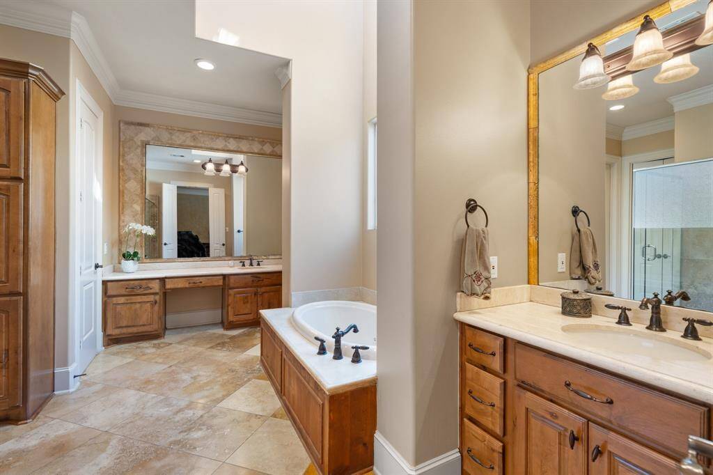Double doors open to this spa-like PRIMARY BATH, offering a luxurious retreat. With travertine floors, two separate vanities (one with a vanity knee space), and large mirrors with vanity lights, this space is designed for convenience and elegance. Ample built-in linen storage is available. Two separate water closets. Two walk-in closets with built-in dressers offer plenty of storage and organization. Recessed lighting, ceiling speakers, and crown molding, enhance the luxurious feel.