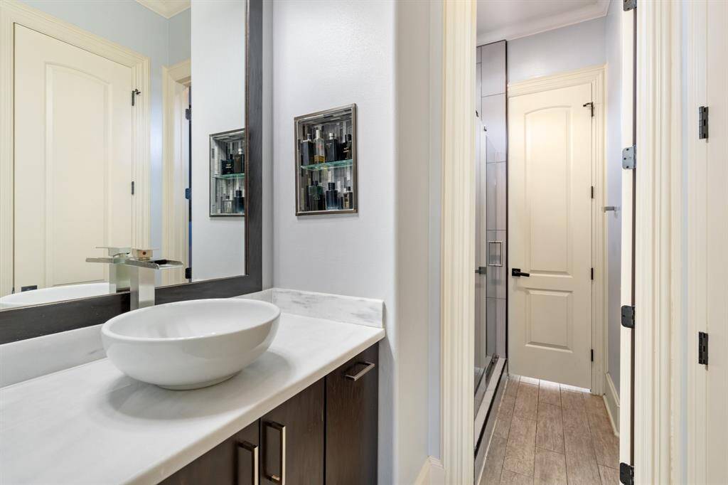 GUEST BATHROOM for SECONDARY BEDROOMS #1 & #2 offers separate and private vanity spaces, each with storage, a vessel sink, a decorative mirror, and vanity lights. A separate room features a walk-in shower with a glass sliding door and a toilet, providing both functionality and privacy for guests or shared use between the two bedrooms.