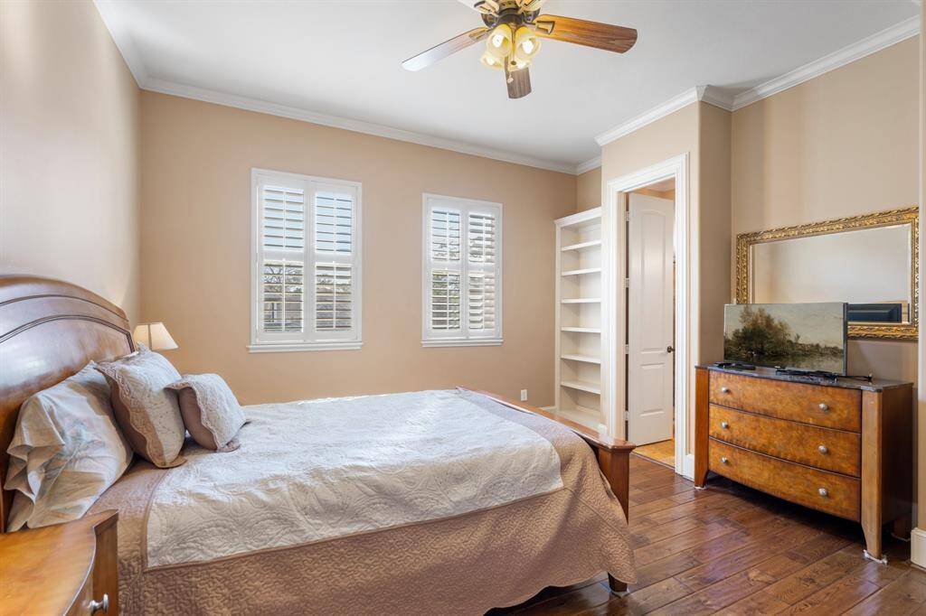 Located upstairs, this spacious SECONDARY BEDROOM #3 offers plenty of room for additional furniture and features built-in bookshelves for added charm and functionality. Hardwood floors, crown molding, and recessed can lighting create an inviting atmosphere, while a ceiling fan/light fixture ensures comfort. Plantation shutters bring in natural light while maintaining privacy. There is a private en-suite bathroom with a walk -in closet.