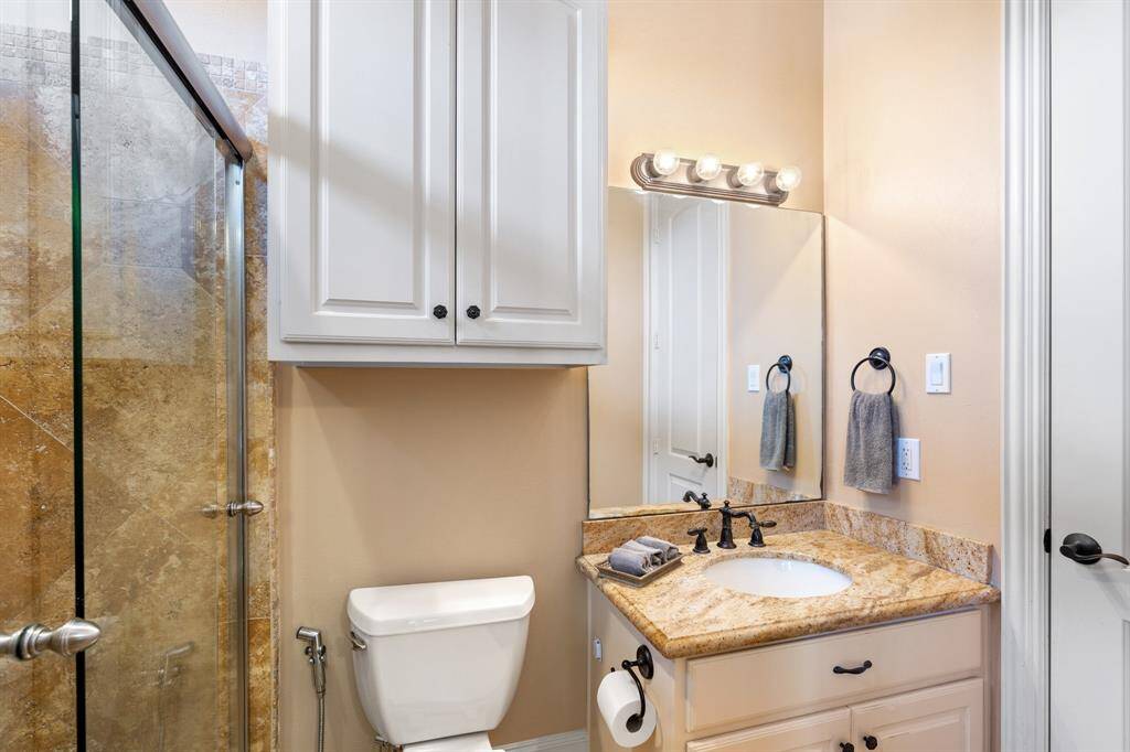 The ensuite bathroom for secondary bedroom #3 includes a walk-in shower with a glass sliding door, a vanity with storage and a headknocker cabinet for extra space, as well as vanity lights for added illumination. A walk-in closet completes the convenience and storage of this private bath.